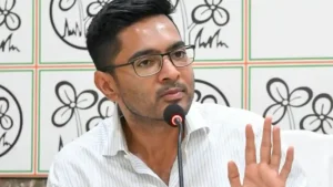 Abhishek Banerjee gestures while speaking into a microphone in front of a wall with Trinamool Congress logos